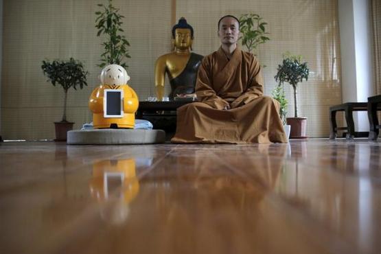 Master Xianfan sits next to robot Xian'er as he poses for photograph at Longquan Buddhist temple on the outskirts of Beijing, April 20, 2016. REUTERS/Kim Kyung-Hoon